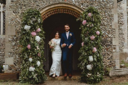 Bride and Groom at wedding flower arch